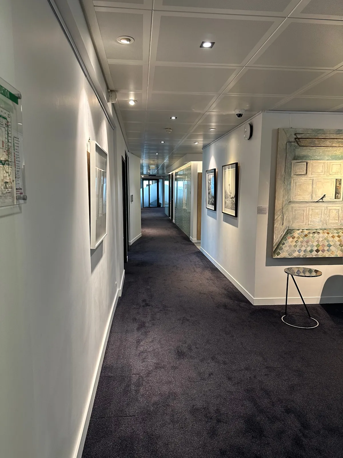 Circulation d'un immeuble de bureaux avec spots encastrés, détection incendie et plan d'évacuation